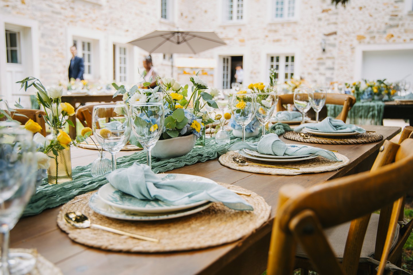 Table de réception de mariage décorée de fleurs, de serviettes bleues et de couverts.