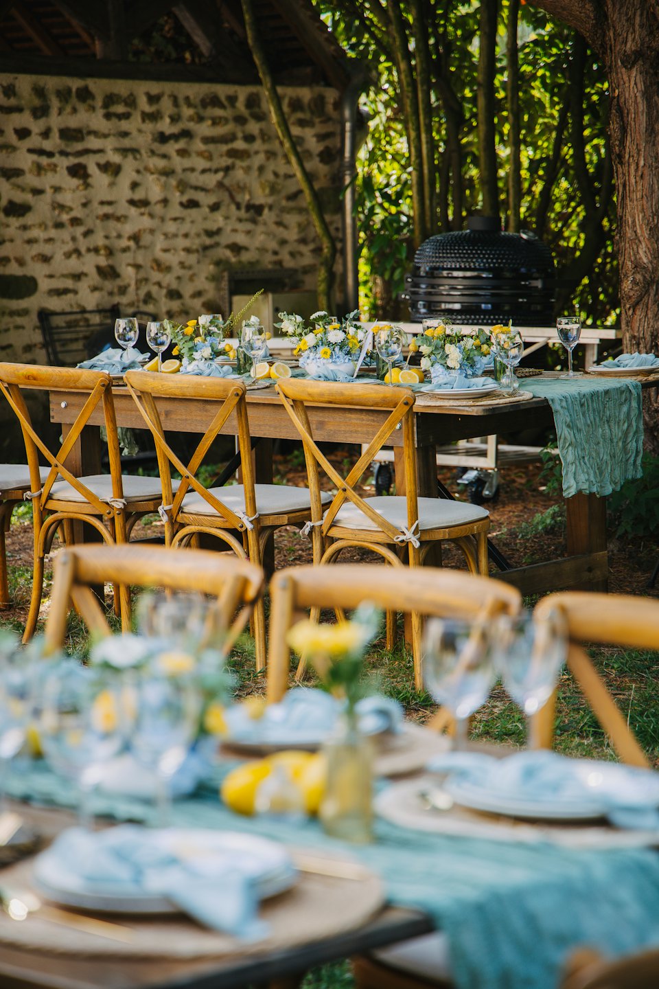 Table de salle à manger extérieure dressée avec des chemins bleus et des centres de table aux citrons.