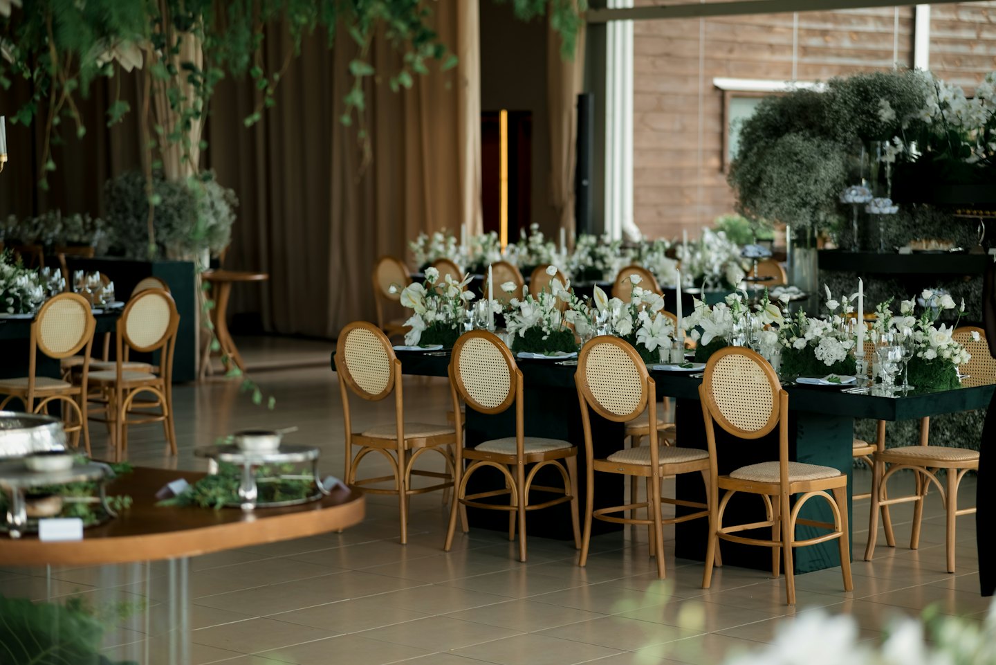 Espace événementiel élégant avec de longues tables, des arrangements floraux et des bougies.