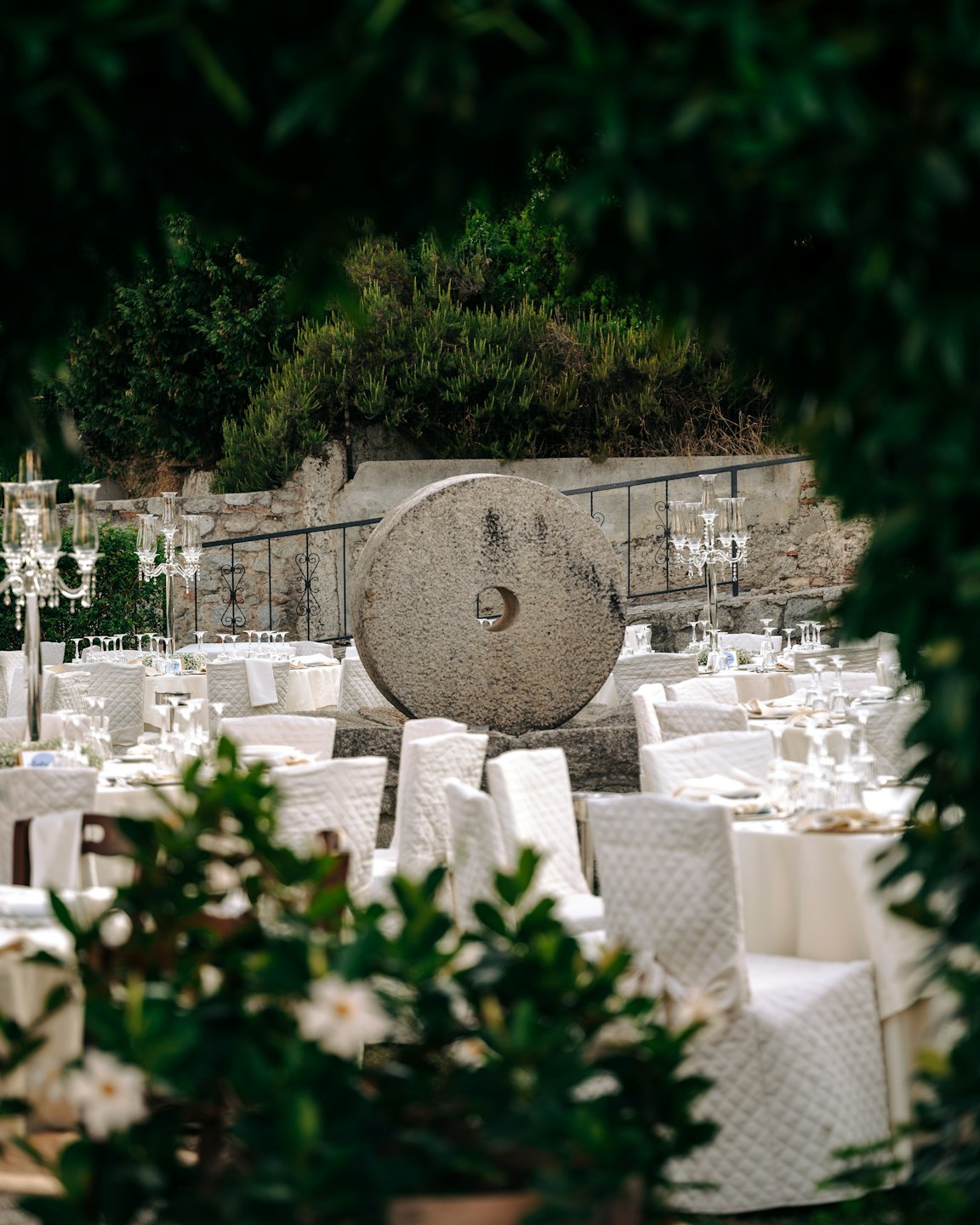 Des tables de réception de mariage élégantes entourent une meule de pierre centrale.