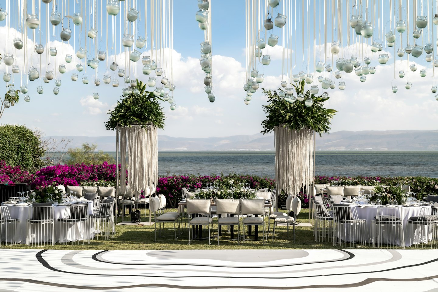 Élégante réception de mariage en plein air avec centres de table floraux et vue sur l'eau.