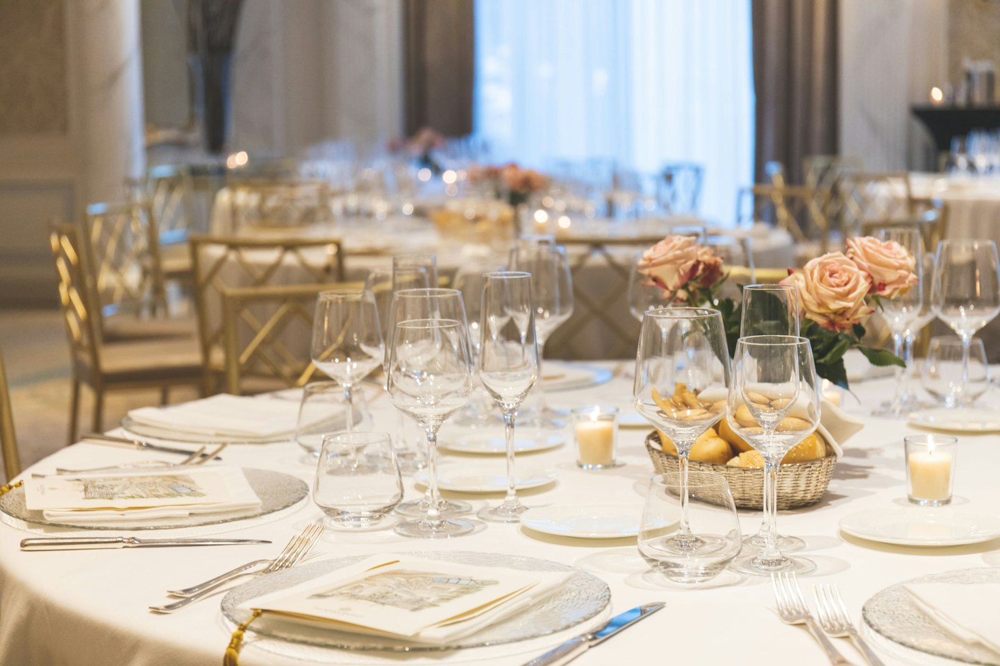 Une table de salle à manger formelle dressée avec des nappes blanches et des roses roses.