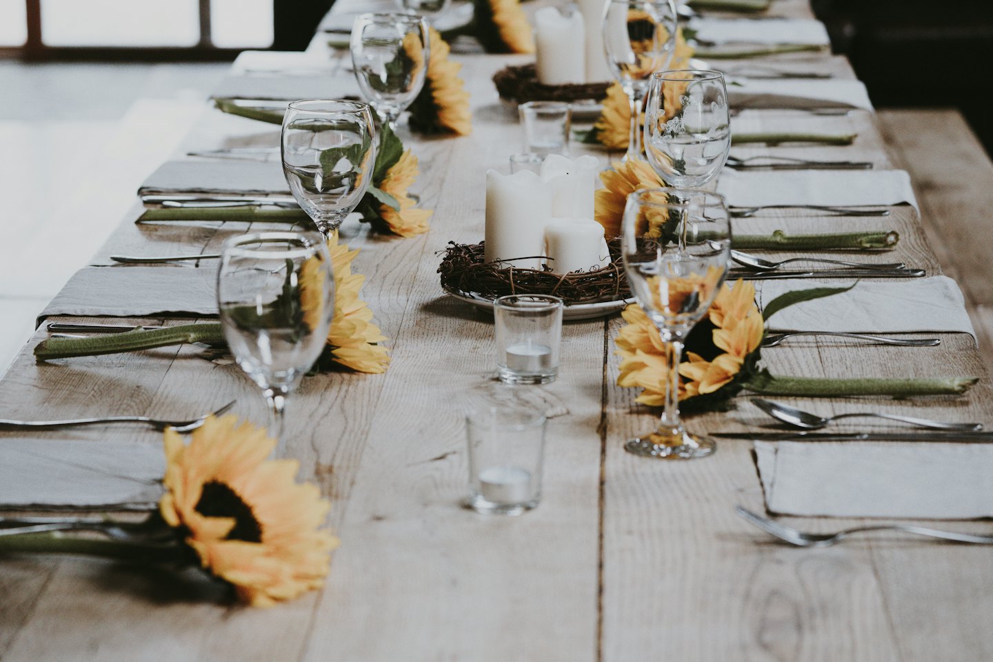 Mise en place de tournesols sur une table en bois rustique.